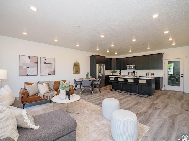living area featuring recessed lighting, light wood-style floors, and a textured ceiling