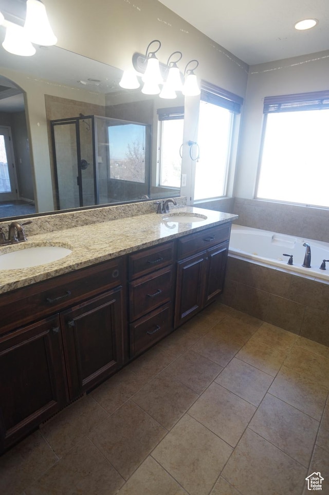 full bath with a bath, double vanity, a sink, and a stall shower