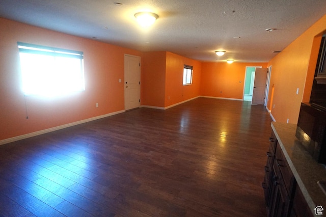 interior space featuring a textured ceiling, baseboards, and dark wood finished floors