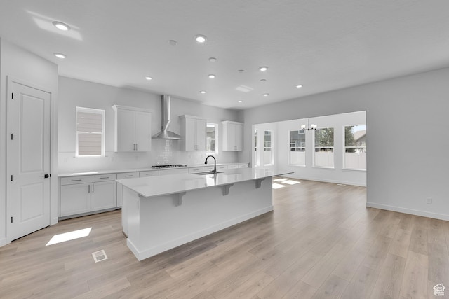 253 E Polaris Dr Unit 105, Saratoga Springs, UT 84045 - kitchen featuring wall chimney exhaust hood, a spacious island, light countertops, light wood-style floors, and a chandelier