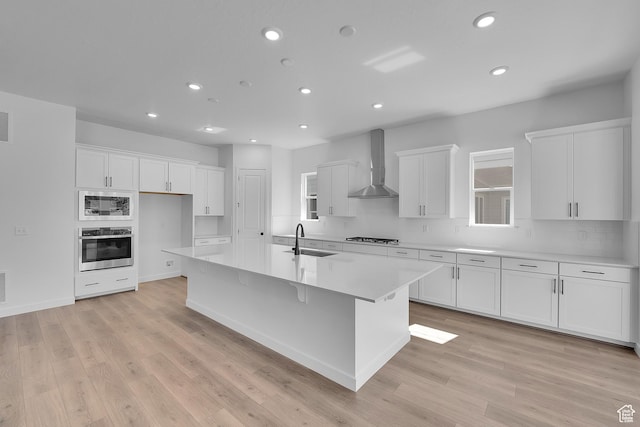 253 E Polaris Dr Unit 105, Saratoga Springs, UT 84045 - kitchen featuring wall chimney exhaust hood, stainless steel appliances, recessed lighting, white cabinetry, and a kitchen island with sink