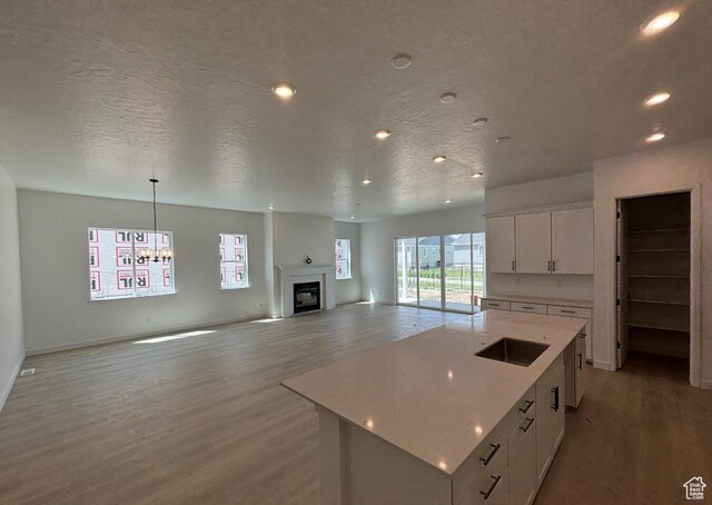 258 E Polaris Dr Unit 110, Saratoga Springs, UT 84045 - kitchen with light wood-style floors, white cabinets, a glass covered fireplace, recessed lighting, and a chandelier