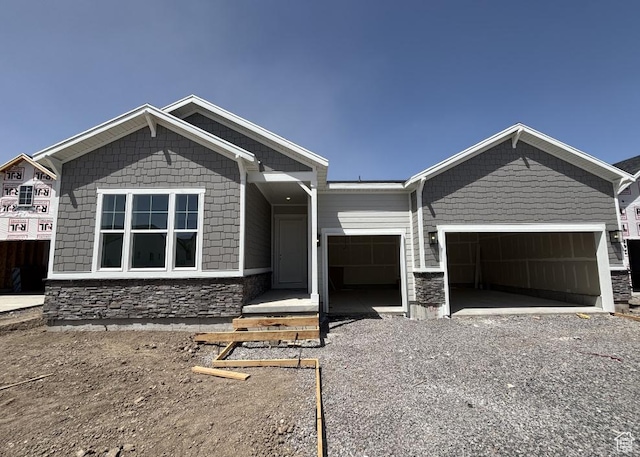 258 E Polaris Dr Unit 110, Saratoga Springs, UT 84045 - view of front facade with stone siding, an attached garage, and gravel driveway