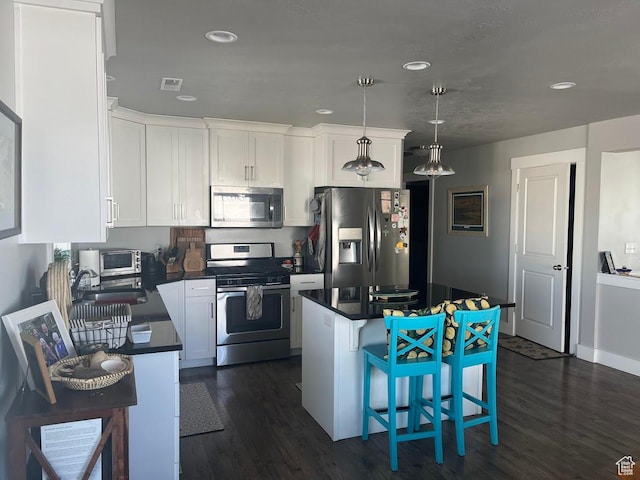 1869 Southpointe Ct, Logan, UT 84341 - kitchen featuring white cabinets, a kitchen bar, dark countertops, appliances with stainless steel finishes, and a sink