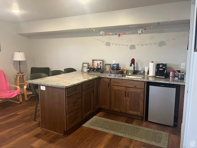 1869 Southpointe Ct, Logan, UT 84341 - kitchen featuring a sink, refrigerator, a breakfast bar, a peninsula, and dark wood-type flooring