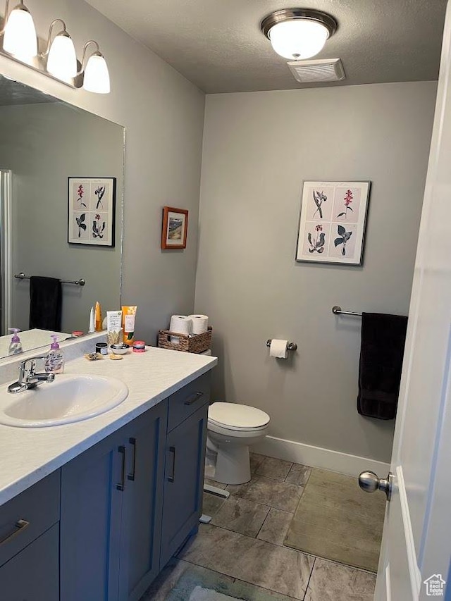 1869 Southpointe Ct, Logan, UT 84341 - bathroom featuring toilet, vanity, a textured ceiling, baseboards, and visible vents