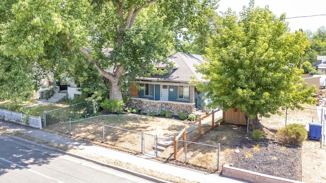 1197 S 700 E, Salt Lake City, UT 84105 - obstructed view of property with a gate, stone siding, a fenced front yard, a shed, and a porch