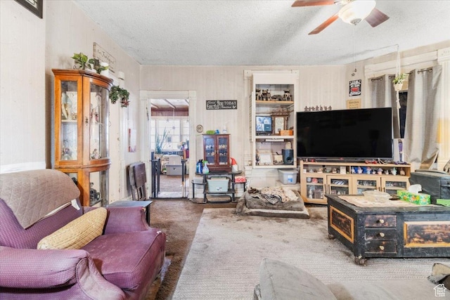 carpeted living area featuring a textured ceiling and a ceiling fan