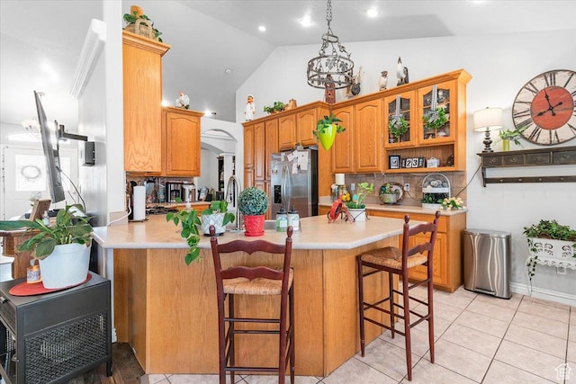 kitchen featuring a breakfast bar area, light countertops, a peninsula, and stainless steel refrigerator with ice dispenser