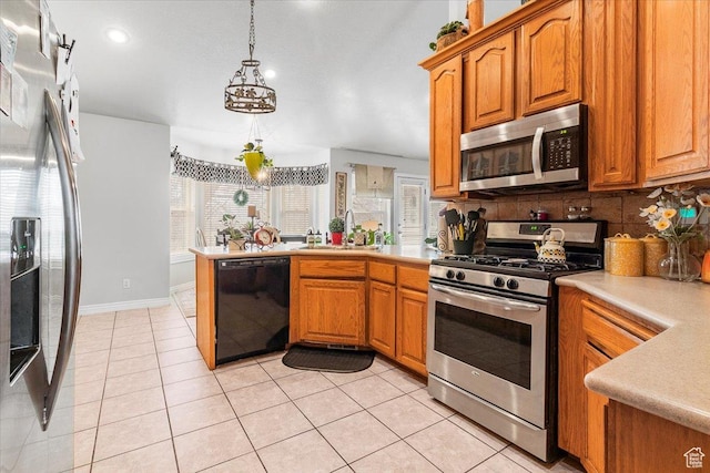 kitchen featuring light countertops, a peninsula, stainless steel appliances, a sink, and backsplash