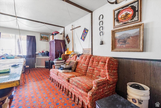 carpeted living area featuring a wainscoted wall, wood walls, and radiator heating unit