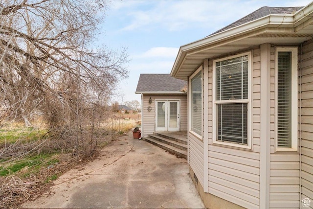 view of side of property featuring roof with shingles and a patio area