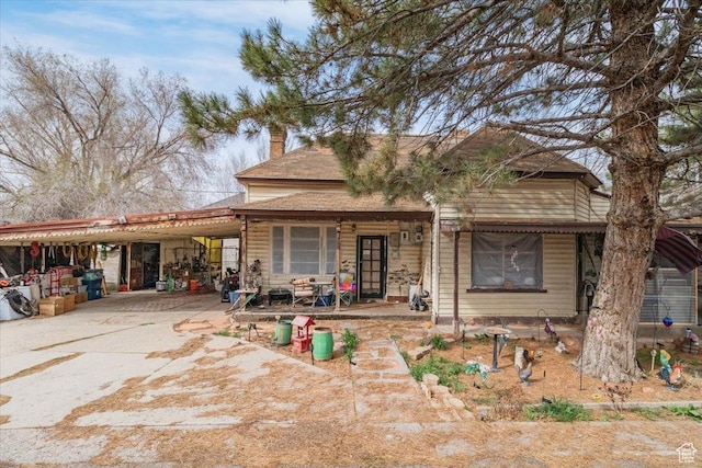 view of front of property with driveway, a carport, and a chimney