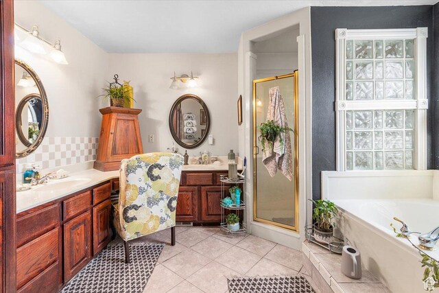 full bathroom with a bathtub, a shower stall, two vanities, a sink, and tile patterned flooring
