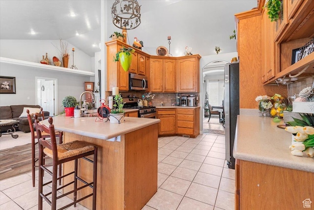 kitchen featuring light tile patterned floors, a peninsula, a sink, and appliances with stainless steel finishes