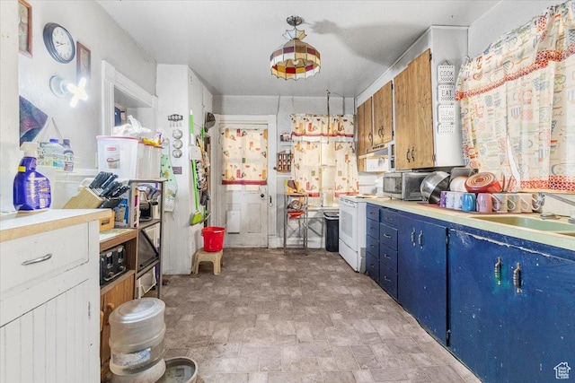 kitchen with blue cabinetry, light countertops, a sink, and white appliances