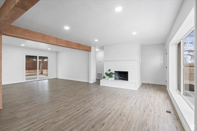 4880 S 4380 W, Salt Lake City, UT 84118 - unfurnished living room with visible vents, a fireplace, wood finished floors, and a healthy amount of sunlight