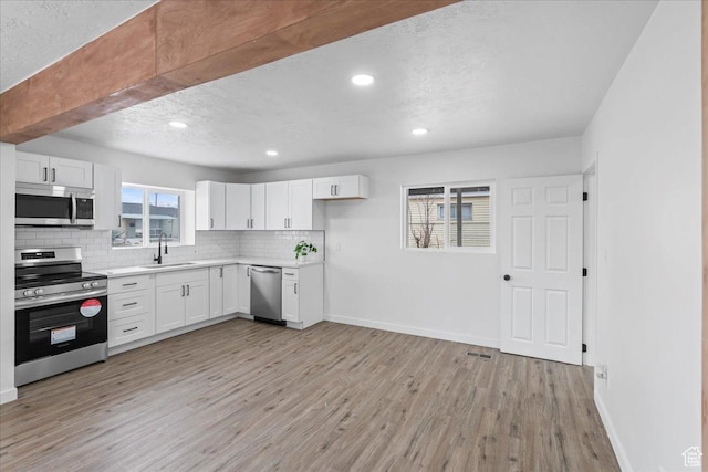 4880 S 4380 W, Salt Lake City, UT 84118 - kitchen featuring light countertops, a sink, appliances with stainless steel finishes, light wood-type flooring, and decorative backsplash