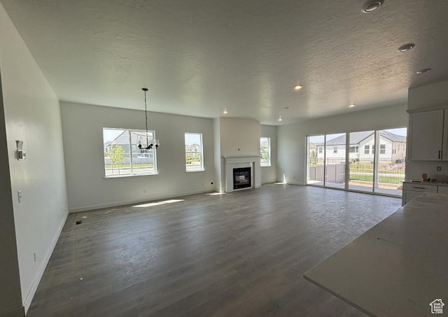 234 E Polaris Dr Unit 108, Saratoga Springs, UT 84045 - unfurnished living room featuring dark wood-type flooring, baseboards, recessed lighting, a chandelier, and a glass covered fireplace