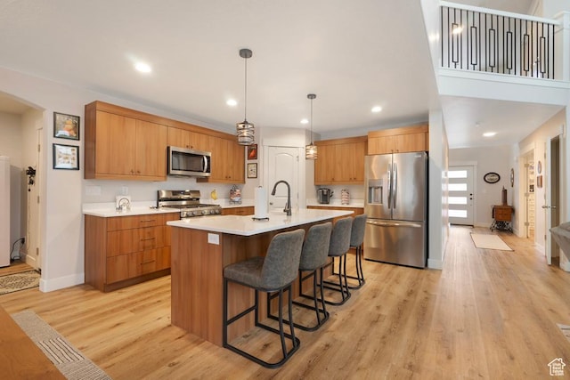 4143 W Gate Keeper Dr, Herriman, UT 84096 - kitchen with appliances with stainless steel finishes, light countertops, a kitchen bar, an island with sink, and light wood-type flooring