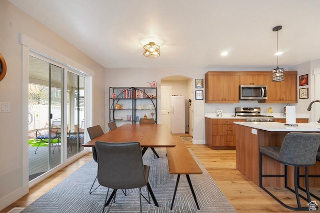 4143 W Gate Keeper Dr, Herriman, UT 84096 - kitchen featuring stove, stainless steel microwave, freestanding refrigerator, arched walkways, and light countertops