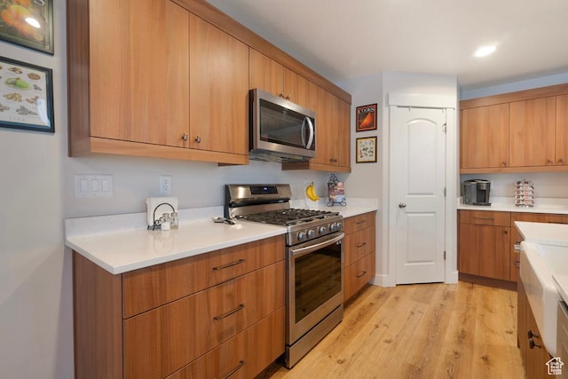 4143 W Gate Keeper Dr, Herriman, UT 84096 - kitchen featuring appliances with stainless steel finishes, light countertops, light wood-type flooring, and brown cabinetry