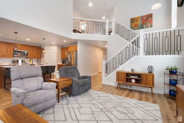 4143 W Gate Keeper Dr, Herriman, UT 84096 - living room featuring a towering ceiling, light wood finished floors, recessed lighting, stairs, and baseboards