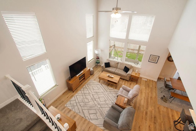 4143 W Gate Keeper Dr, Herriman, UT 84096 - living room with a high ceiling, baseboards, ceiling fan, and light wood-style flooring