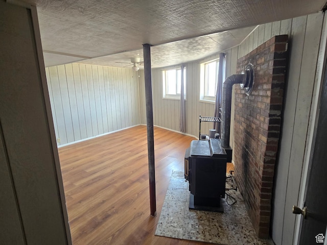3379 S 1750 E, Price, UT 84501 - interior space featuring wooden walls, baseboards, ceiling fan, wood finished floors, and a wood stove