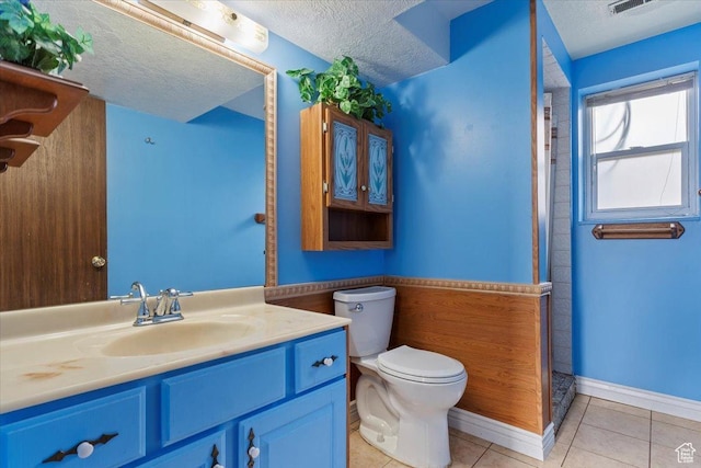 bathroom featuring a shower, toilet, vanity, a textured ceiling, and tile patterned flooring