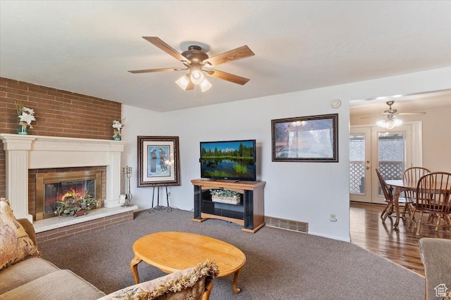 carpeted living room with visible vents, a ceiling fan, and a brick fireplace