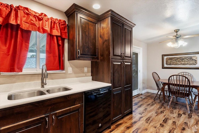 kitchen with a ceiling fan, light countertops, a sink, black dishwasher, and wood finished floors
