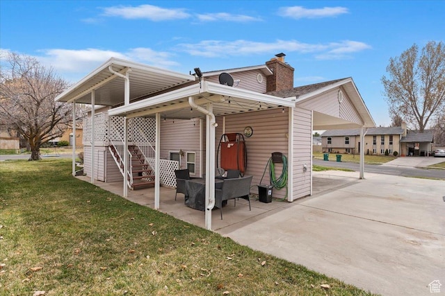 back of property with a chimney, a patio area, stairway, and a yard