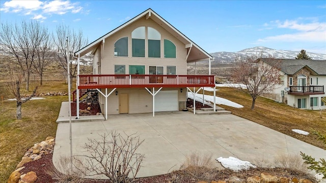 792 S Spruce Dr S, Garden City, UT 84028 - back of property featuring driveway, an attached garage, a deck with mountain view, and a yard