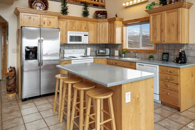 792 S Spruce Dr S, Garden City, UT 84028 - kitchen with light tile patterned flooring, a sink, a center island, white appliances, and decorative backsplash