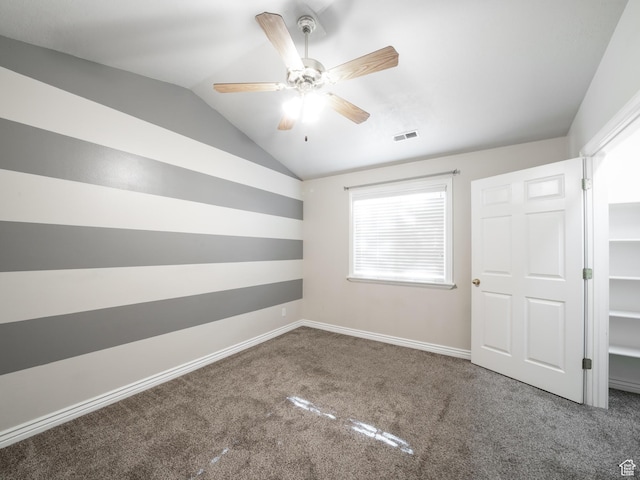 unfurnished bedroom with carpet flooring, visible vents, baseboards, ceiling fan, and lofted ceiling