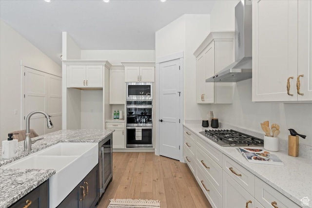 3779 S Old Wood, West Valley City, UT 84120 - kitchen with stainless steel appliances, a sink, white cabinetry, wall chimney exhaust hood, and light wood-style flooring