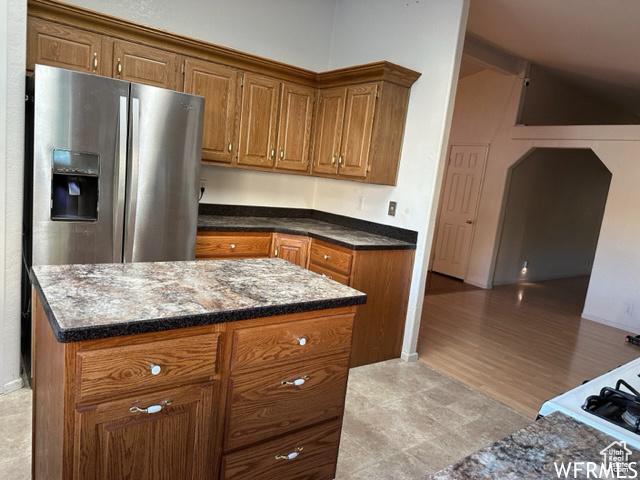 2103 S Mountain Vista Ln E, Provo, UT 84606 - kitchen with dark stone countertops, stainless steel fridge, brown cabinetry, and a kitchen island