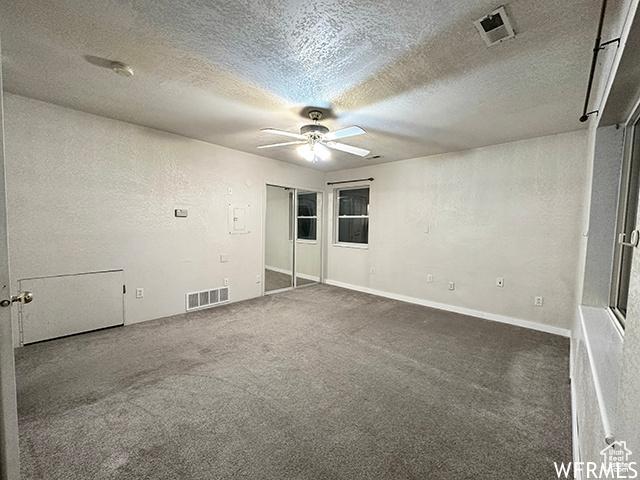 2103 S Mountain Vista Ln E, Provo, UT 84606 - empty room featuring a textured ceiling, ceiling fan, visible vents, and dark colored carpet