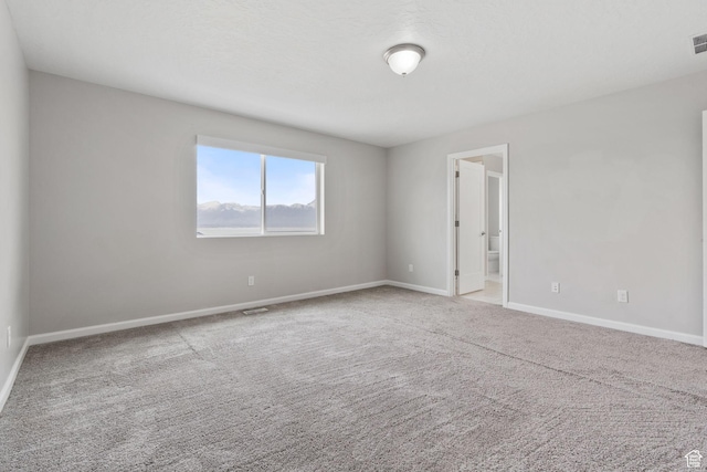 carpeted spare room with baseboards and visible vents