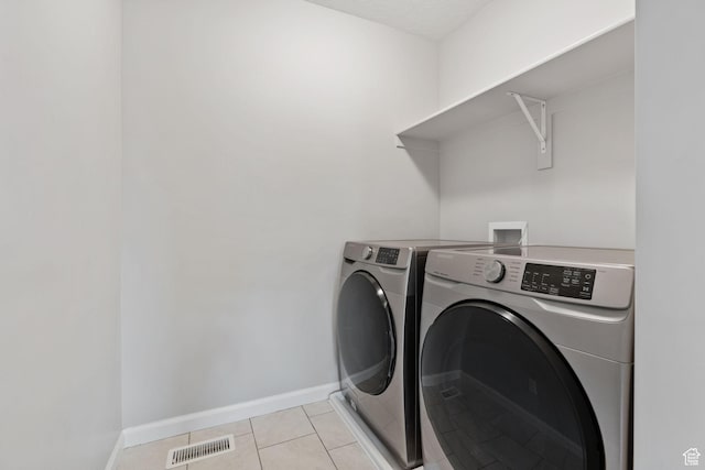 laundry area featuring light tile patterned floors, baseboards, separate washer and dryer, visible vents, and laundry area