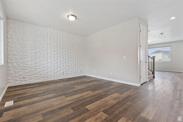 unfurnished room with baseboards, visible vents, wood finished floors, and stairway