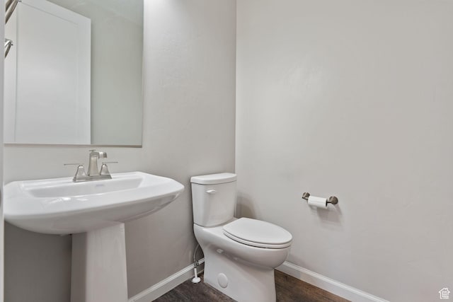 half bath featuring baseboards, toilet, and wood finished floors