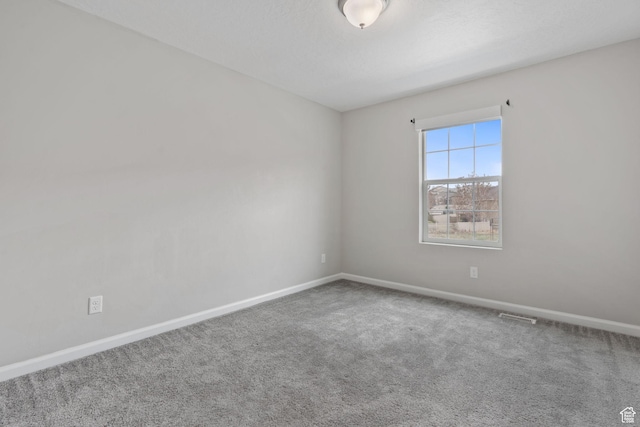 empty room featuring carpet floors, baseboards, and visible vents
