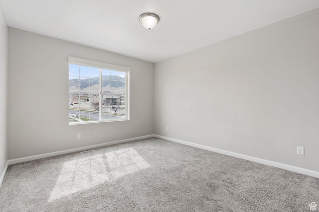 empty room with baseboards, carpet floors, and visible vents