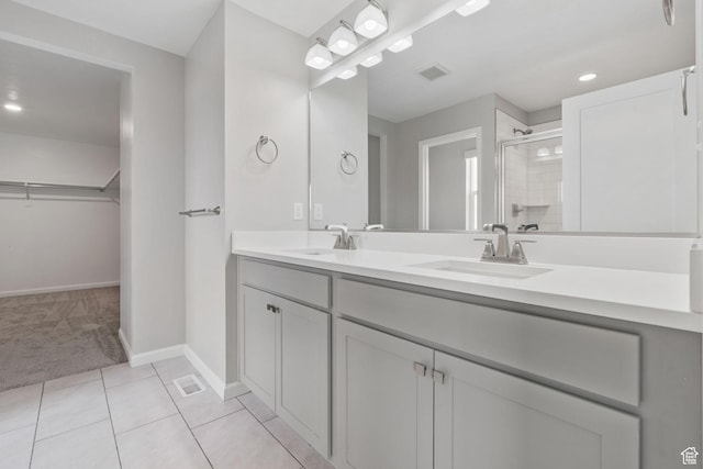 full bathroom with a sink, a walk in closet, a stall shower, and visible vents