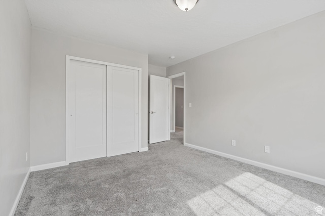 unfurnished bedroom with carpet, a closet, and baseboards