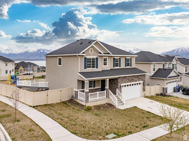 traditional-style house featuring stucco siding, covered porch, a mountain view, and fence private yard