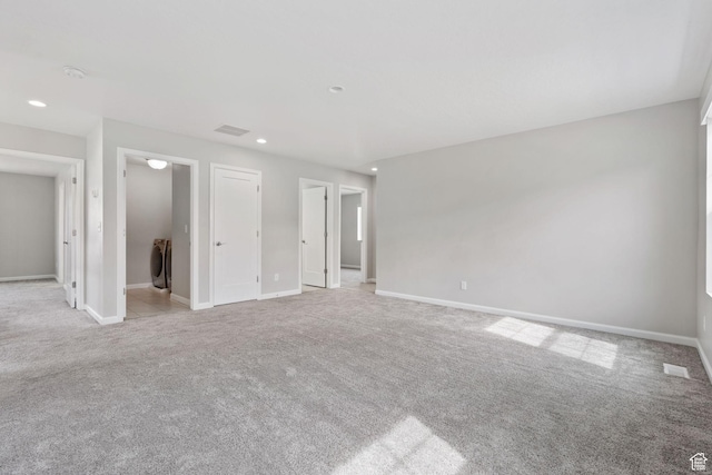 interior space featuring washer / dryer, baseboards, light colored carpet, and visible vents