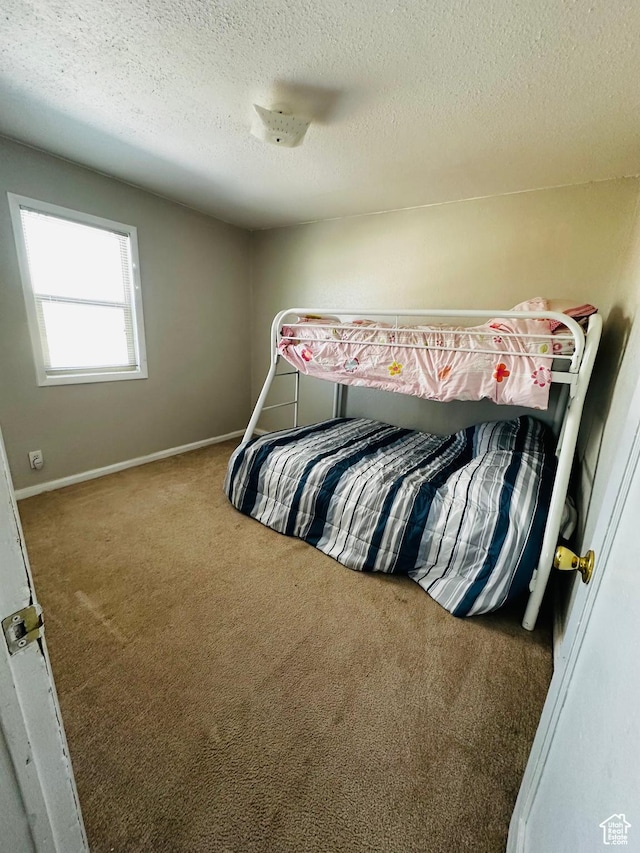 bedroom with a textured ceiling, carpet flooring, and baseboards